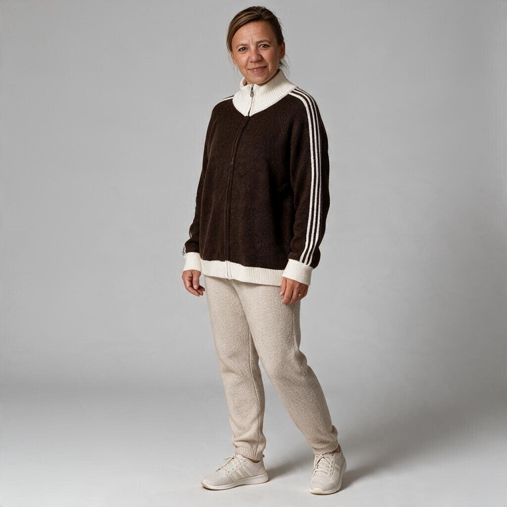 Eine Frau trägt eine braune jamalto Strickjacke mit Reißverschluss, Stehkragen und weißen Streifendetails an den Ärmeln