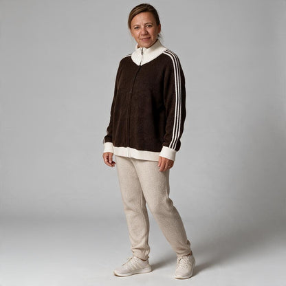 Eine Frau trägt eine braune jamalto Strickjacke mit Reißverschluss, Stehkragen und weißen Streifendetails an den Ärmeln