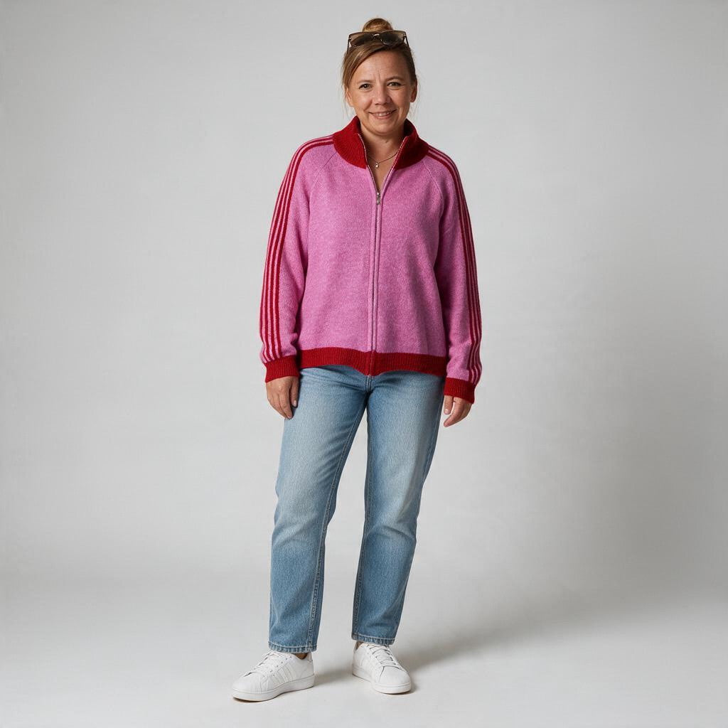 Eine Frau trägt eine jamalto Strickjacke in Pink mit roten Streifendetails, Stehkragen und Reißverschluss zu Jeans.